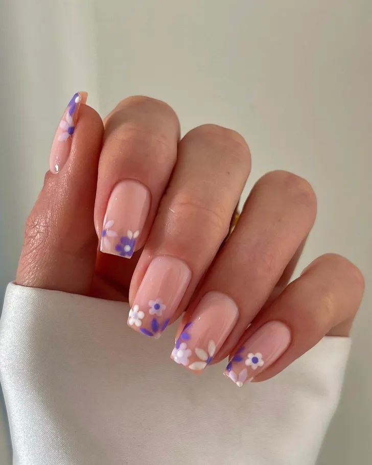 Pink floral nails with delicate red and pink flowers - romantic hand showcasing soft pink base with vibrant red and pink flower petals, featuring green leaves and stems on oval-shaped nails